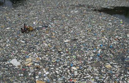 Un padre y su hijo en una balsa de fabricación casera recogen botellas de un río lleno de basura que posteriormente venderán en Manila. Ganan tres dólares diarios por esta labor.