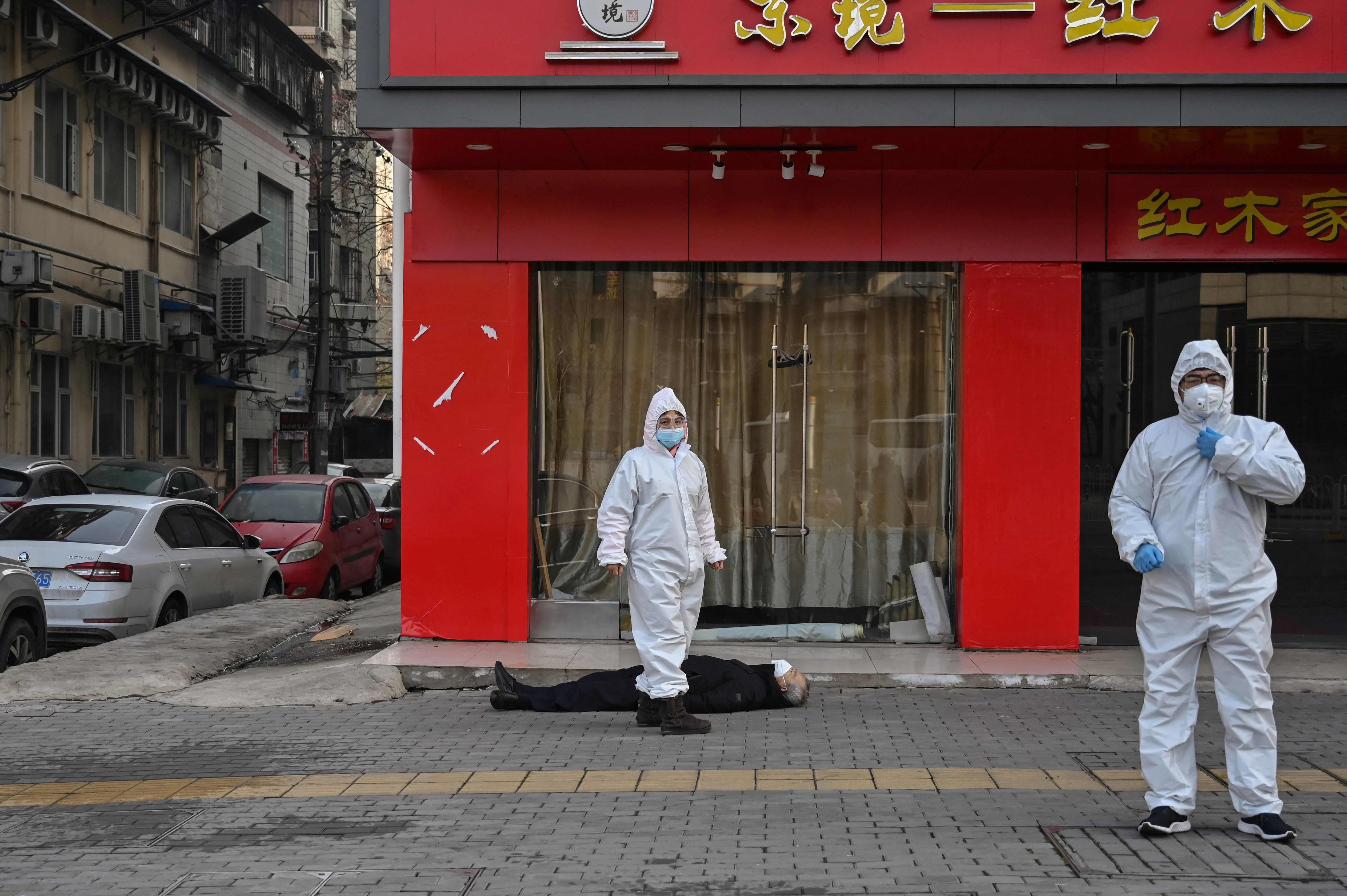 Personal sanitario junto a un hombre muerto cerca de un hospital en Wuhan, el 30 de enero de 2020.