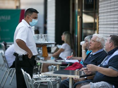 Dos clientes de un bar piden bebidas a un camarero en la plaza de Cataluña.