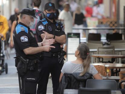 Dos agentes de la pollcía local de A Coruña se dirigen a un hombre que se encontraba fumando en una terraza de un bar de la ciudad.