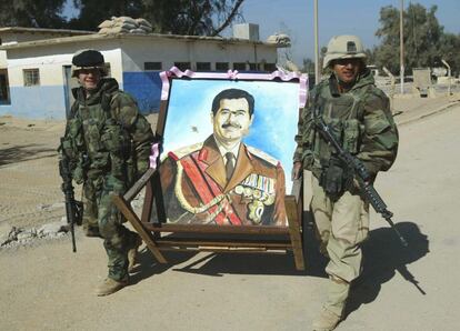 Los sargentos Michael Magri y Peter Aguirre portan un retrato de Sadam Husein en Nayaf, el 2 de abril de 2003.