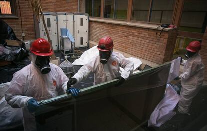 Trabajadores retiran una de las pizarras con amianto en un colegio de Cataluña.