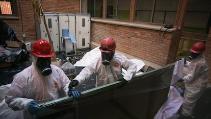 Trabajadores retiran una pizarra con amianto en un colegio de Cataluña.