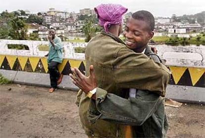 Soldados fieles a Taylor y rebeldes del LURD se abrazan en un puente de Monrovia.