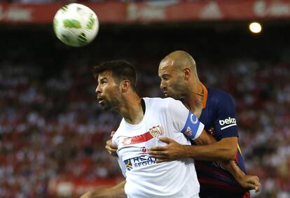 El defensa del Sevilla Coke salta por el balón ante el jugador del Barcelona, Mascherano.