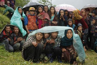 Habitants de Gumda esperen sota la pluja l'arribada d'un helicòpter.