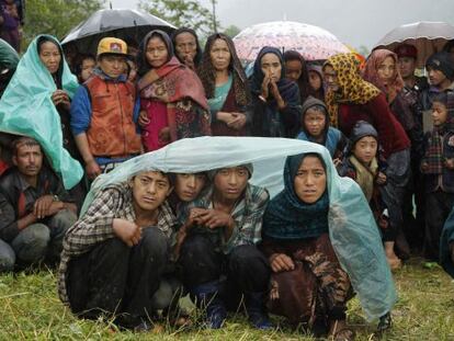 Habitants de Gumda esperen sota la pluja l'arribada d'un helicòpter.