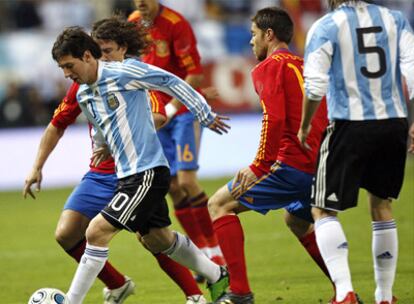 Messi intenta marcharse de Puyol y Xabi Alonso.