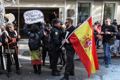 Un manifestante junto a un policía durante la protesta ante la sede del PSOE en Madrid.