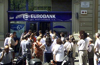 Decenas de clientes de Eurobank hacen cola, ayer, en una de las oficinas de Barcelona para retirar sus ahorros.