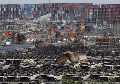 Miembros del personal de emergencias caminan entre los restos de vehículos calcinados en el puerto de Tianjin (China). El Gobierno chino confirmó la existencia de al menos 700 toneladas de cianuro de sodio en el almacén del puerto de Tianjin en el que el miércoles se produjeron dos masivas explosiones, lo que amenaza el bienestar de la ciudad y pone al Ejecutivo del país en un nuevo aprieto.