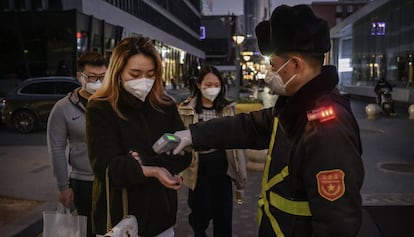 Clientes de un centro comercial en Beijing, China, sometiéndose a un control antes de acceder.