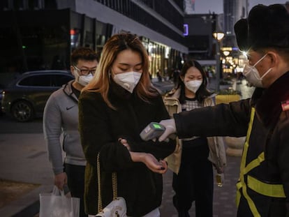 Clientes de un centro comercial en Beijing, China, sometiéndose a un control antes de acceder.