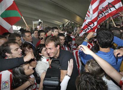 El jugador del Athletic Yeste, en el centro, entre una nube de seguidores rojiblancos en el aeropuerto a Loiu.