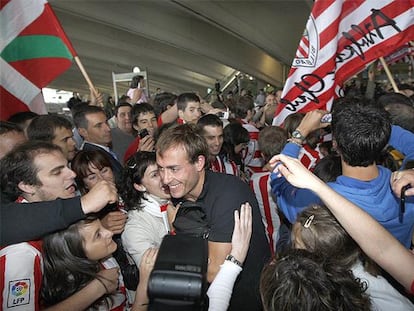 El jugador del Athletic Yeste, en el centro, entre una nube de seguidores rojiblancos en el aeropuerto a Loiu.