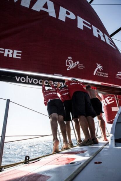 Varios miembros del Mapfre empujan la vela.