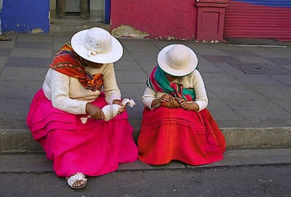 Dos mujeres vestidas de cholas, el traje tradicional indígena de Bolivia. Su papel como pilar de la economía boliviana es clave, especialmente en el comercio.