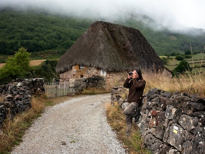 Sofía G. Berdasco, de Somiedo Experience, observando fauna salvaje junto a una cabaña de 'teito' en el concejo de Somiedo (Asturias).