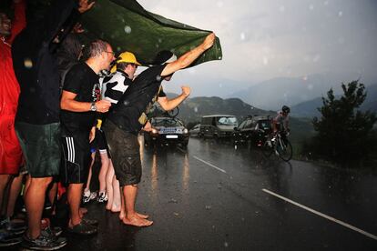 Los aficionados se protegen de la lluvia al paso de los ciclistas durante la contrarreloj entre Embrun y Chorges