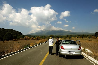 Una pareja observa el volcán desde la carretera.