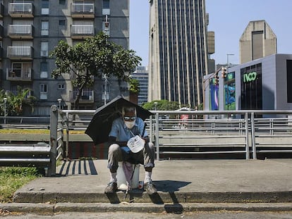 Um homem pede esmola sentado na avenida Libertador, na capital da Venezuela.