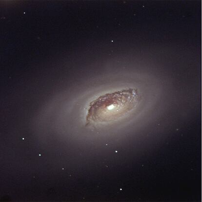 La galaxia Messier 64 (M64), también conocida como Ojo Negro u Ojo del Diablo, se encuentra en la constelación de Coma Berenice, a unos 16 millones de años-luz de la Tierra. Una espectacular banda de polvo alrededor de su brillante núcleo le confiere el aspecto de un ojo negro. A primera vista, M64 parece una galaxia espiral normal, donde todas sus estrellas rotan en la misma dirección. Sin embargo, el gas interestelar de las regiones más externas de la galaxia rota en dirección opuesta. Parece ser que M64 absorbió una pequeña galaxia satélite de la que no quedan restos, salvo este extraordinario comportamiento dinámico. La imagen fue obtenida con la cámara CCD del telescopio de 1 metro de diámetro Jacobus Kapteyn instalado en el Observatorio del Roque de los Muchachos en la isla de La Palma. Texto: Javier Méndez.