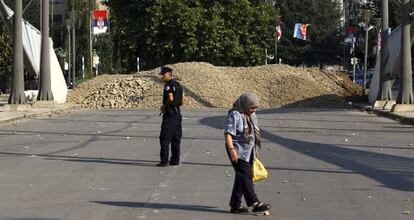 Una mujer camina junto al controvertido puente de Mitrovica.