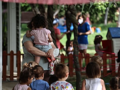 Una profesora sostiene en brazos a una niña en el jardín de la Escuela Infantil municipal Valdelaparra en el término de Alcobendas, que colinda por el norte con la ciudad de Madrid.