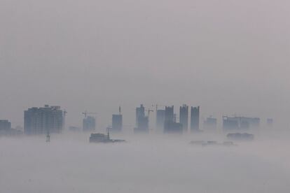 Las azoteas de los rascacielos se dejan ver entre la densa niebla de Huaian (China).