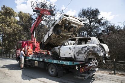 Un operario retira dos coches calcienados en la localidad griega de Mati, el 25 de julio de 2018.