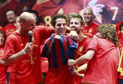 Pepe Reina y Carles Puyol, junto a Piqué (detrás), ponen la camiseta del Barcelona a Cesc Fábregas, durante la celebración de los jugadores de la selección española en Madrid, tras ganar el Mundial de Sudáfrica 2010.