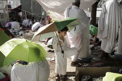 Un niño lleva un paraguas para esconderse del sol cerca de la tienda de campaña que aloja al resto de su familia en Arafat. 