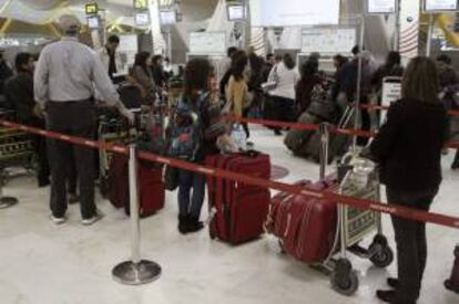 Pasajeros hacen cola en los terminales de facturación de Iberia de la T4 de Barajas Madrid. EFE/Archivo