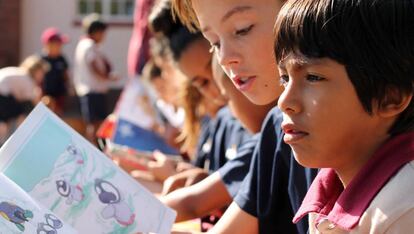 Un alumno de más edad leyéndole un cuento a otro pequeño durante el recreo. 