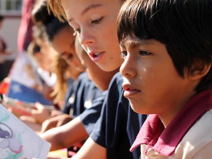 Un alumno de más edad leyéndole un cuento a otro pequeño durante el recreo. 