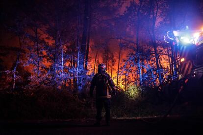 Un bombero permanecía esta madrugada junto a su vehículo mientras continuaban los trabajos de extinción del incendio forestal declarado cerca de Belin-Béliet, en el suroeste de Francia.