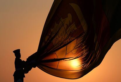 Un oficial de las Fuerzas Aéreas de Sri Lanka sostienen la bandera nacional mientras desciende como parte de una ceremonia diaria durante la puesta de sol en el paseo de Galle Face Green en Colombo.