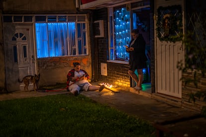 Dos mujeres salen al exterior de su vivienda para encender las velas, en la localidad de Suba (Bogotá).