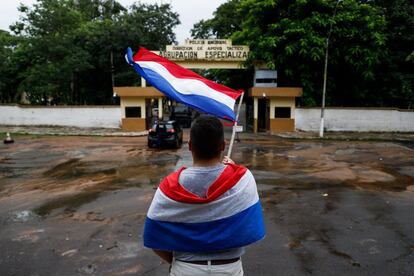 Un partidario del Partido Liberal ondea una bandera nacional, frente a la sede de la Agrupación Especializada, donde el líder opositor paraguayo Efraín Alegre cumple cinco días en prisión preventiva, en Asunción (Paraguay).