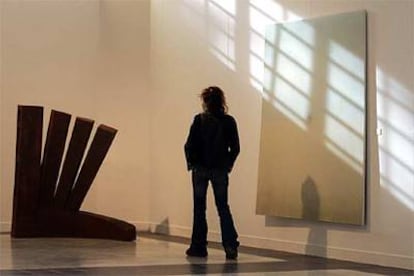 Un visitante observa la obra <b><i>Asedio,</b></i> a la izquierda, de Patxi Gutiérrez.