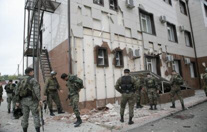 Varios soldados de una fuerza especial, ante el edificio del Parlamento, que muestra los estragos de la explosión.