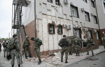 Varios soldados de una fuerza especial, ante el edificio del Parlamento, que muestra los estragos de la explosión.