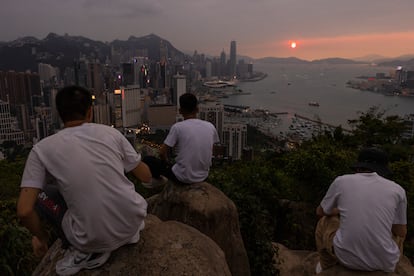 Mainland Chinese tourists look at sunset from a hill in Hong Kong