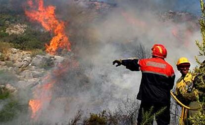 Dos bomberos luchan contra las llamas en el incendio forestal de Benissa.