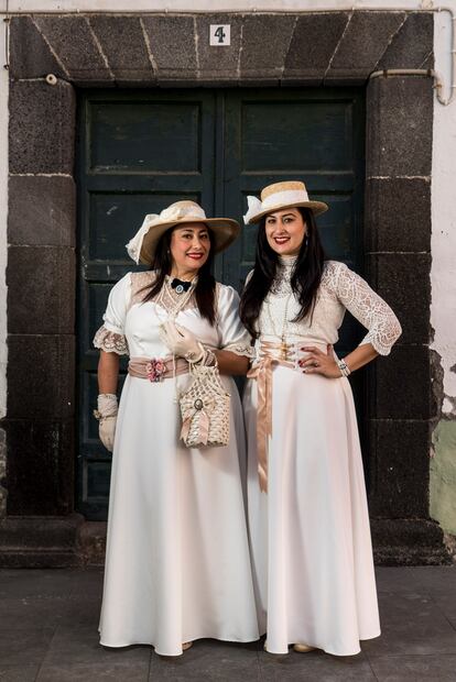 El disfraz de las indianas consiste en vestidos de finales del siglo XIX y principios del XX con detalles refinados como encajes y blondas, complementados con sombreros decorados con flores, guantes, sombrillas, abanicos y joyas. Este elegante conjunto refleja la influencia colonial y el estilo de las mujeres palmeras que regresaron de América.