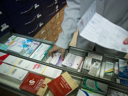 Un farmacéutico busca un medicamento indicado en una receta en Barcelona.