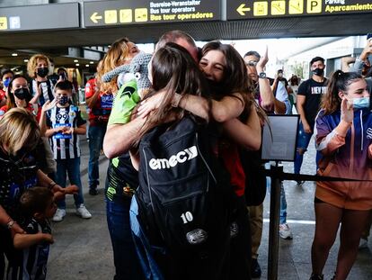 Una chica joven abraza a sus padres en un aeropuerto en 2021.