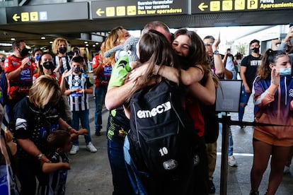 Una chica joven abraza a sus padres en un aeropuerto en 2021.