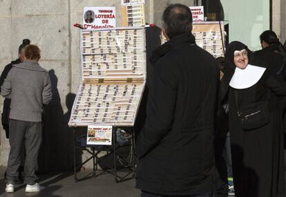 Una monja, junto a un puesto de venta ambulante de lotería en la Puerta del Sol, en Madrid, el 3 de diciembre de 2015.