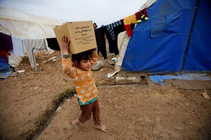 Una niña lleva una caja de cartón mientras su familia empaqueta sus pertenencias para volver a su casa en Mosul desde el campo de Hamam al-Alil (Irak).
